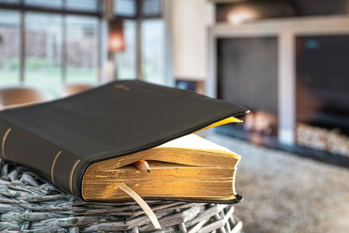 Bible book with pencil, on the background of the living room. Reading a book in a cozy environment.