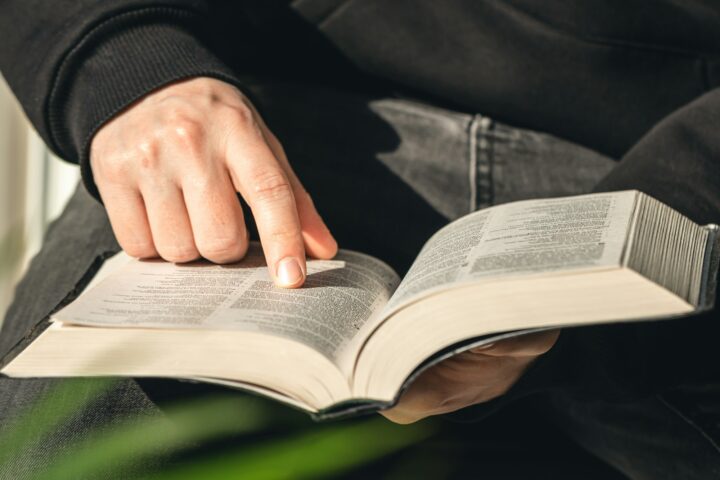 Open book Bible in male hands, close-up.
